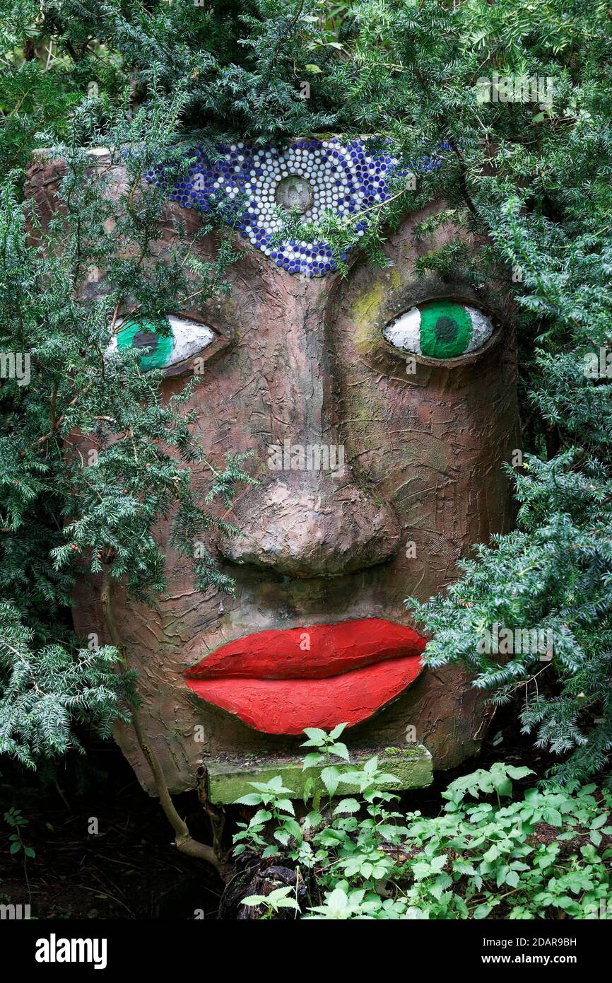 Magical woman face with red lips and green eyes looks through branches, sculpture, sculpture garden by the artist Jochen Bach, Plinzmuehle, Plinz Stock Photo