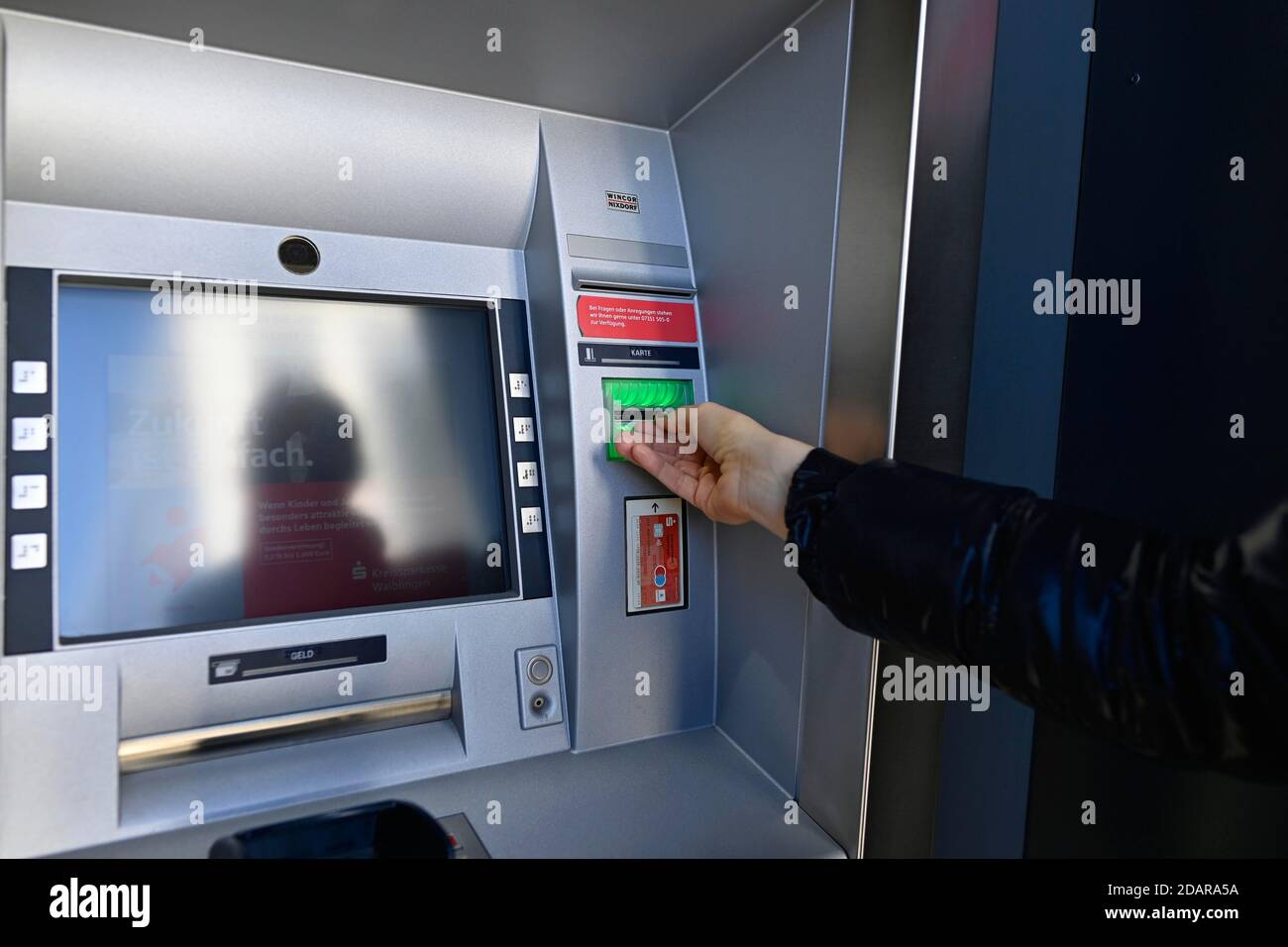 Woman waiting for the ec-card at the cash dispenser of a savings bank, Waiblingen, Baden-Wuerttemberg, Germany Stock Photo