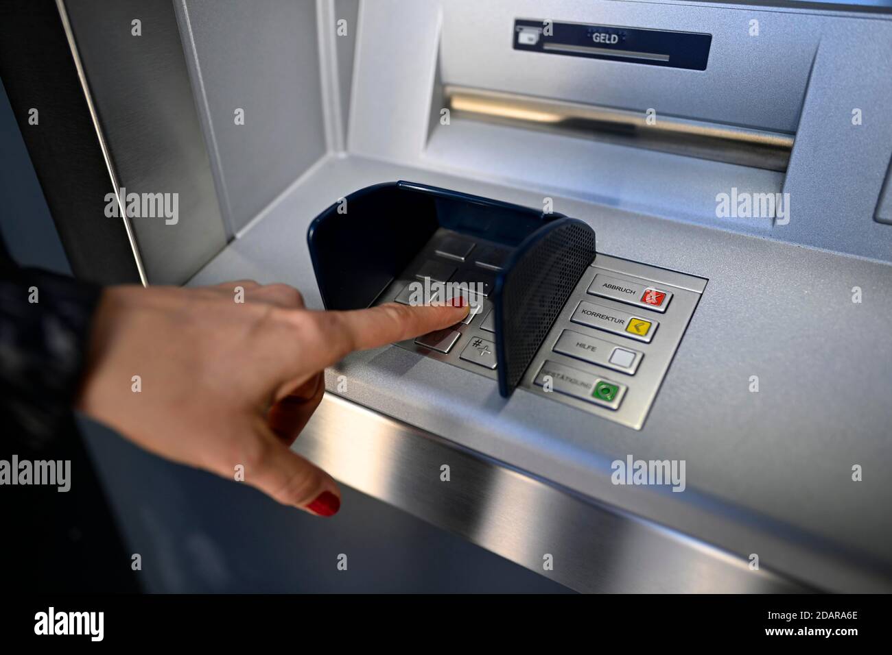 Woman typing in secret code at the cash machine of a savings bank ...