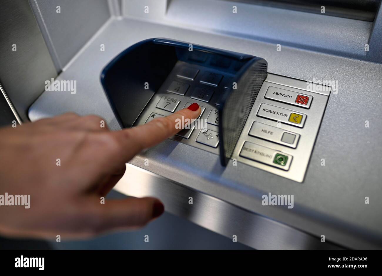 Woman typing in secret code at the cash machine of a savings bank ...