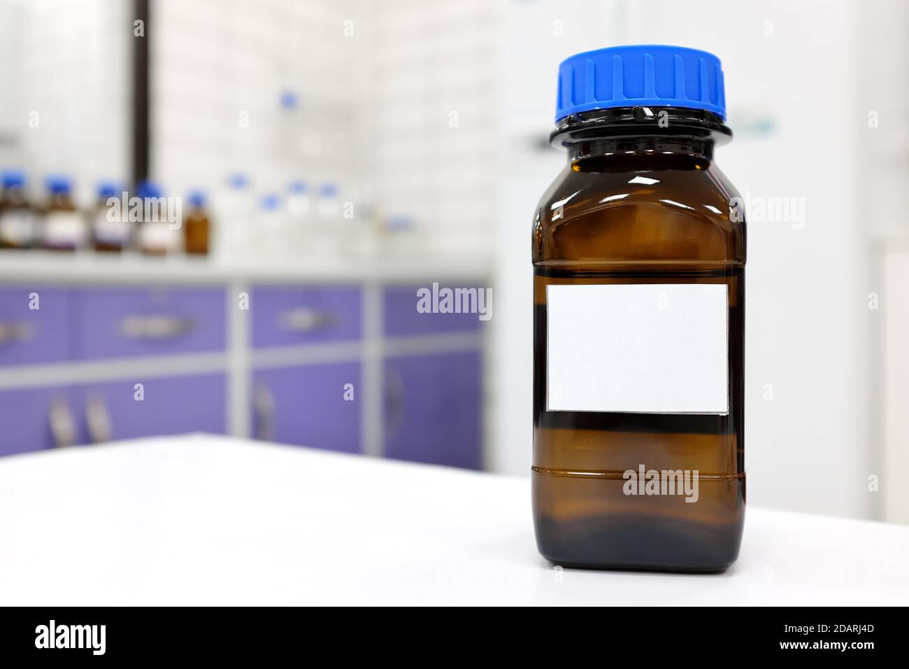 Selective focus of dark glass reagent bottle with unknown clear liquid