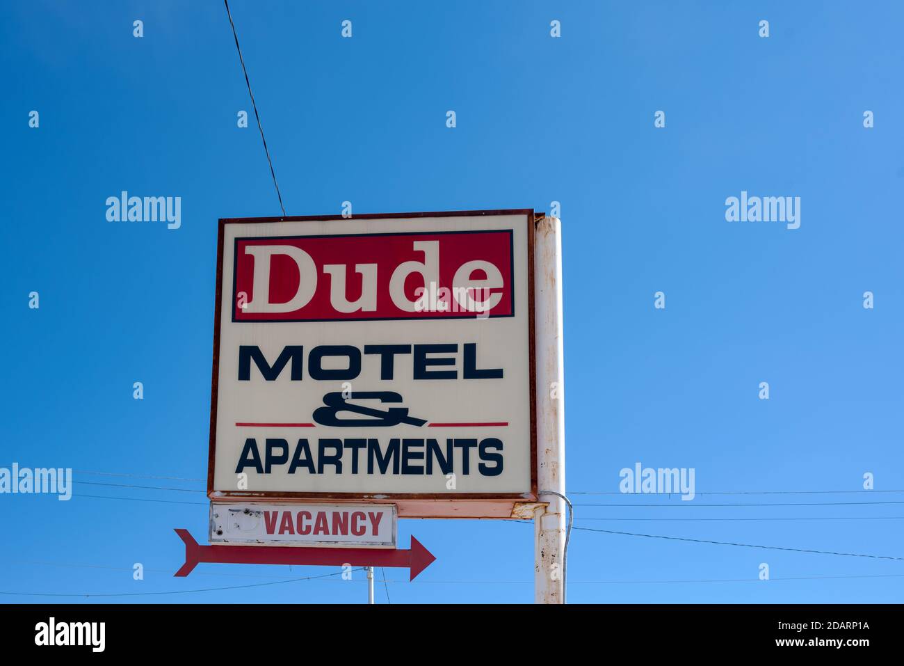 A red and white sign backed by a blue sky advertises a vacancy for motel rooms and apartments in the Dude Motel in Truth or Consequences, New Mexico. Stock Photo