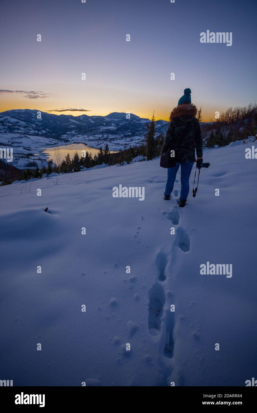Photographers photographing winter lake mountain scene in sunset, alone in wilderness. Rovni, Valjevo, Serbia Stock Photo