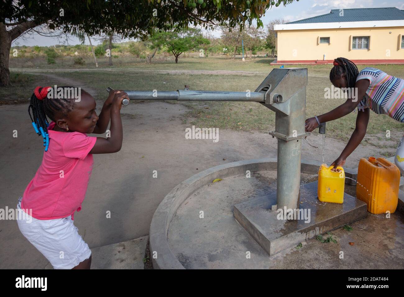Young girls getting fresh water in the community hand water pump in rural Africa Stock Photo