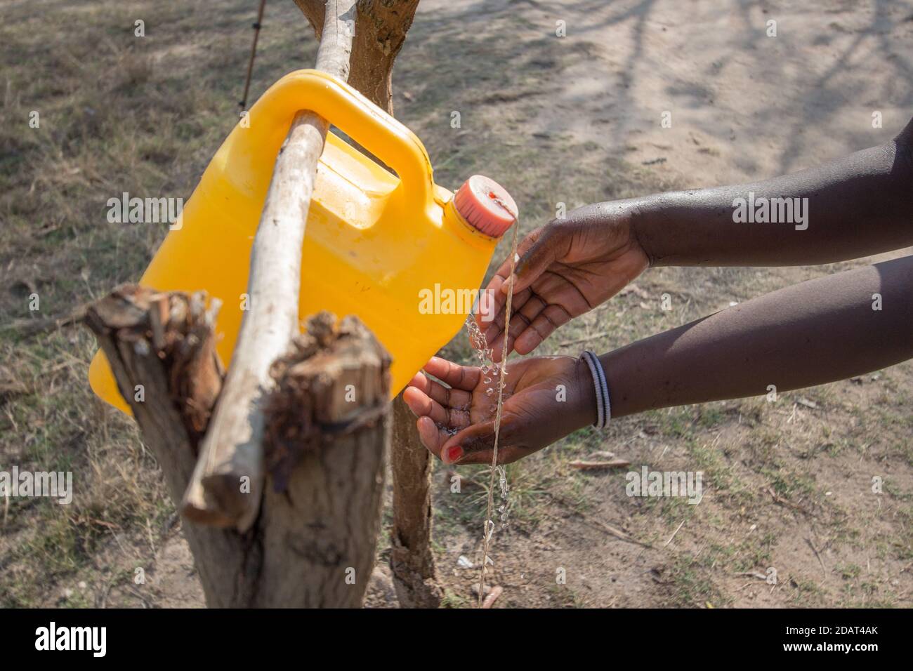 Hand washing innovation called tippy tap made of 5 liter can of water and a string, supported by two tree logs Stock Photo
