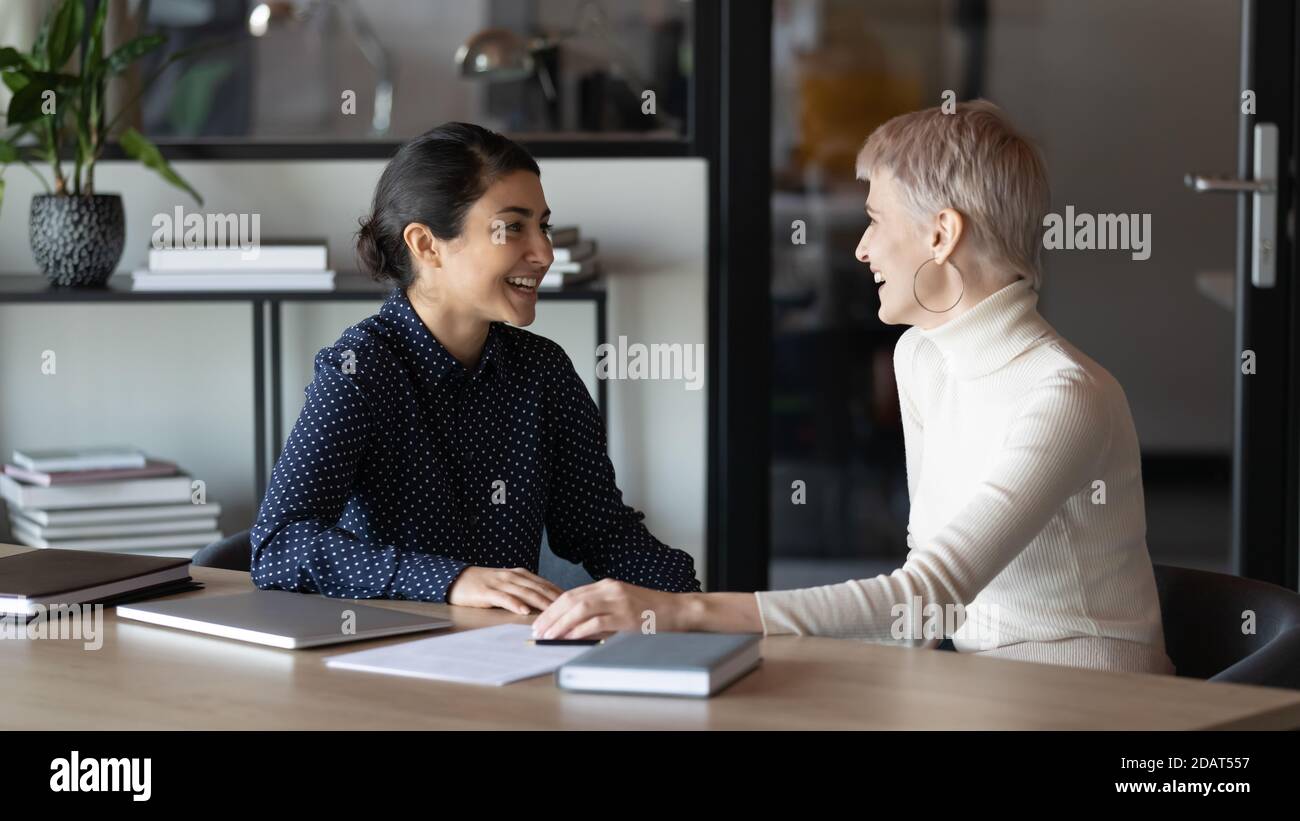 Happy diverse colleagues chatting during break, having pleasant conversation Stock Photo