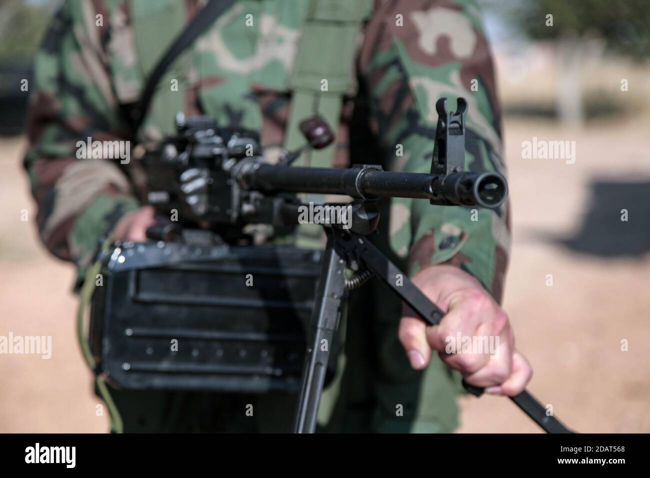 North Homs, Syria - 2017: Soldier Fighter Standing while Holding and Pointing Russian BKC Automatic Machine Gun during Syrian Civil War | Close up Stock Photo