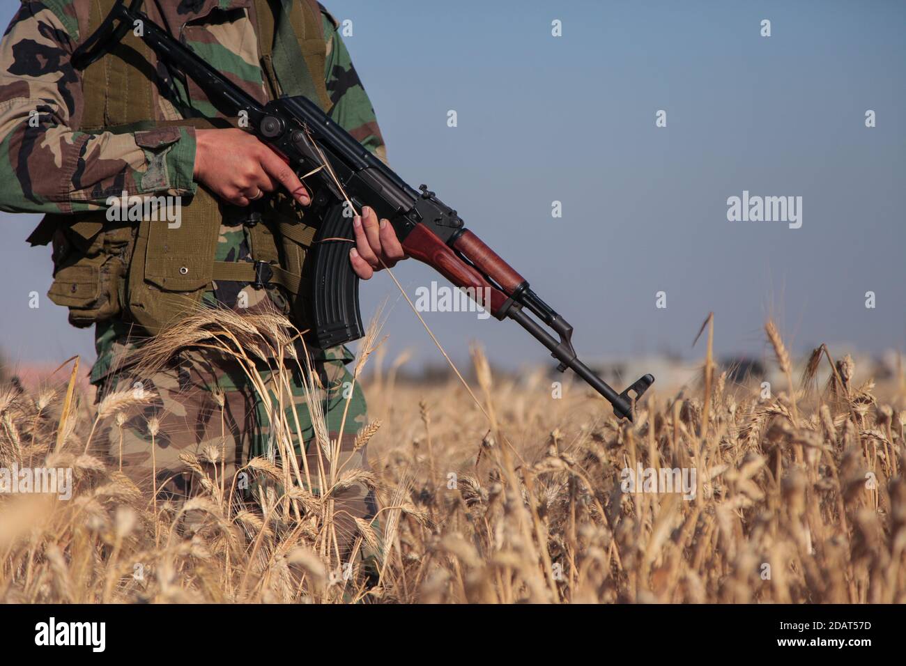 North Homs, Syria 2017: Syrian Soldier Fighter Holding AKS Russian Machine Gun during Syrian Civil War Standing in an agricultural country wheat field Stock Photo