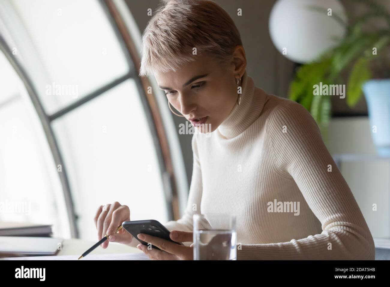 Close up confident businesswoman using phone, checking documents Stock Photo