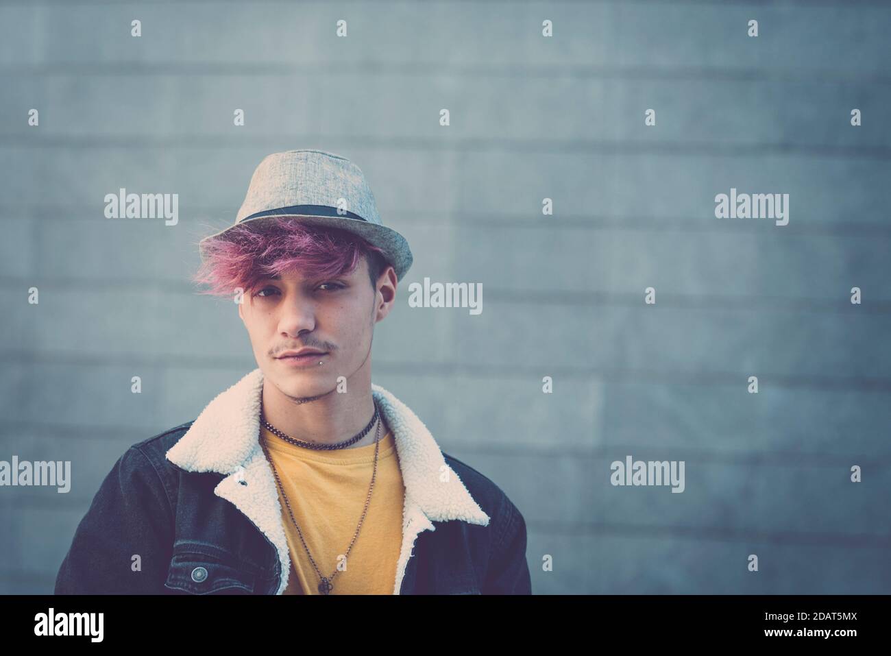 Portrait of handsome alternative trendy young man teenager boy with violet hair and hat - youth people with piercing and coloured hair looking on came Stock Photo