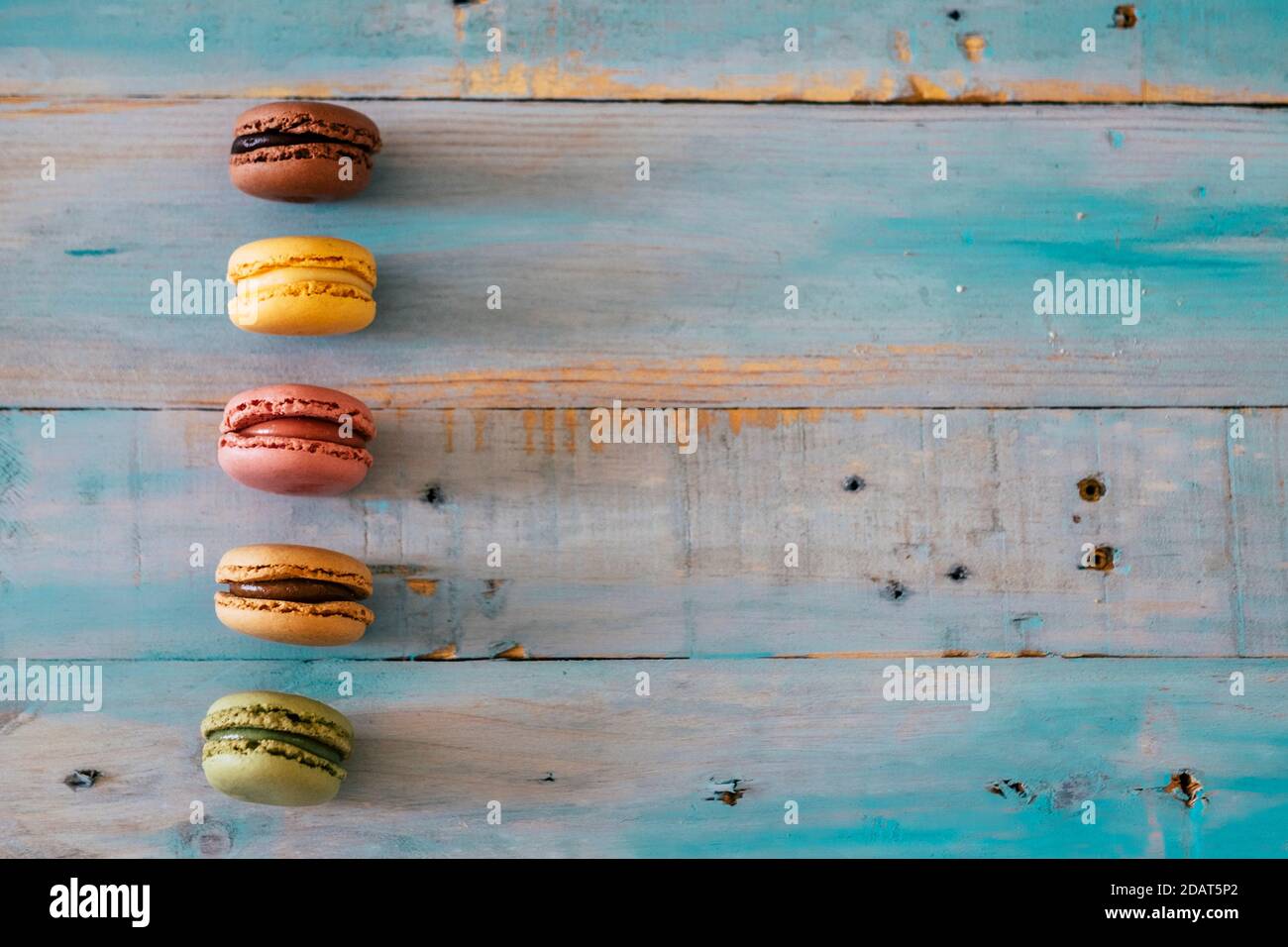 Background blue wooden table with five macarones with chocolate and cream - sugar tasty cakes cookies Stock Photo