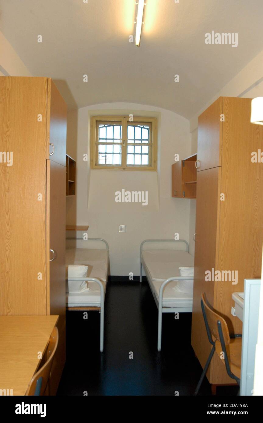 inside a prison cell with two beds, closets, desks and chairs Stock