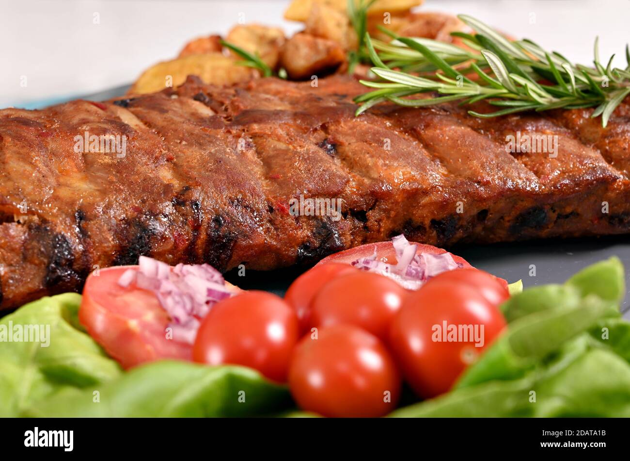 pork spare ribs potatoeas and tomatoes at plate Stock Photo