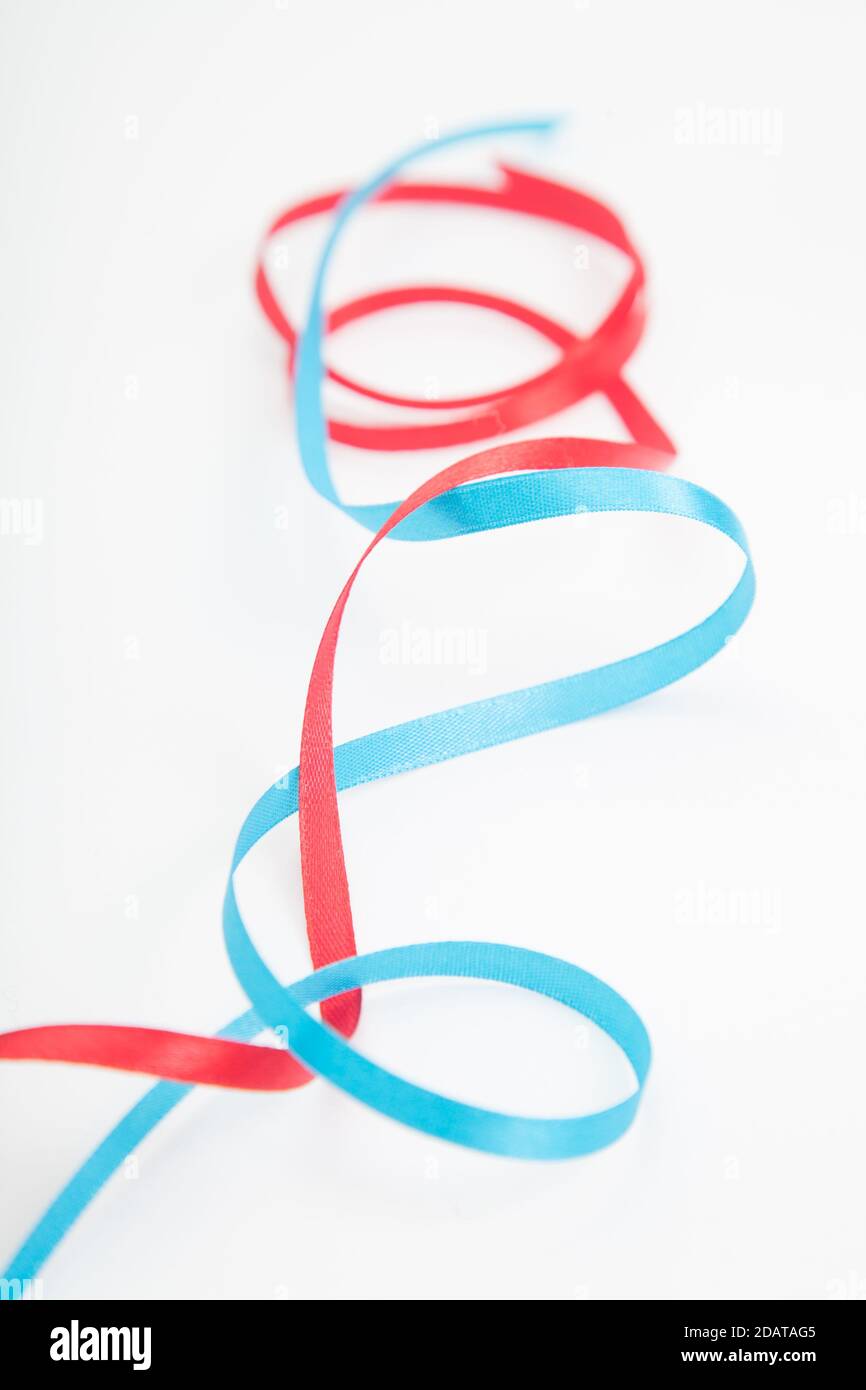 Closeup of vertical interweaving red and blue wavy ribbons on white ...