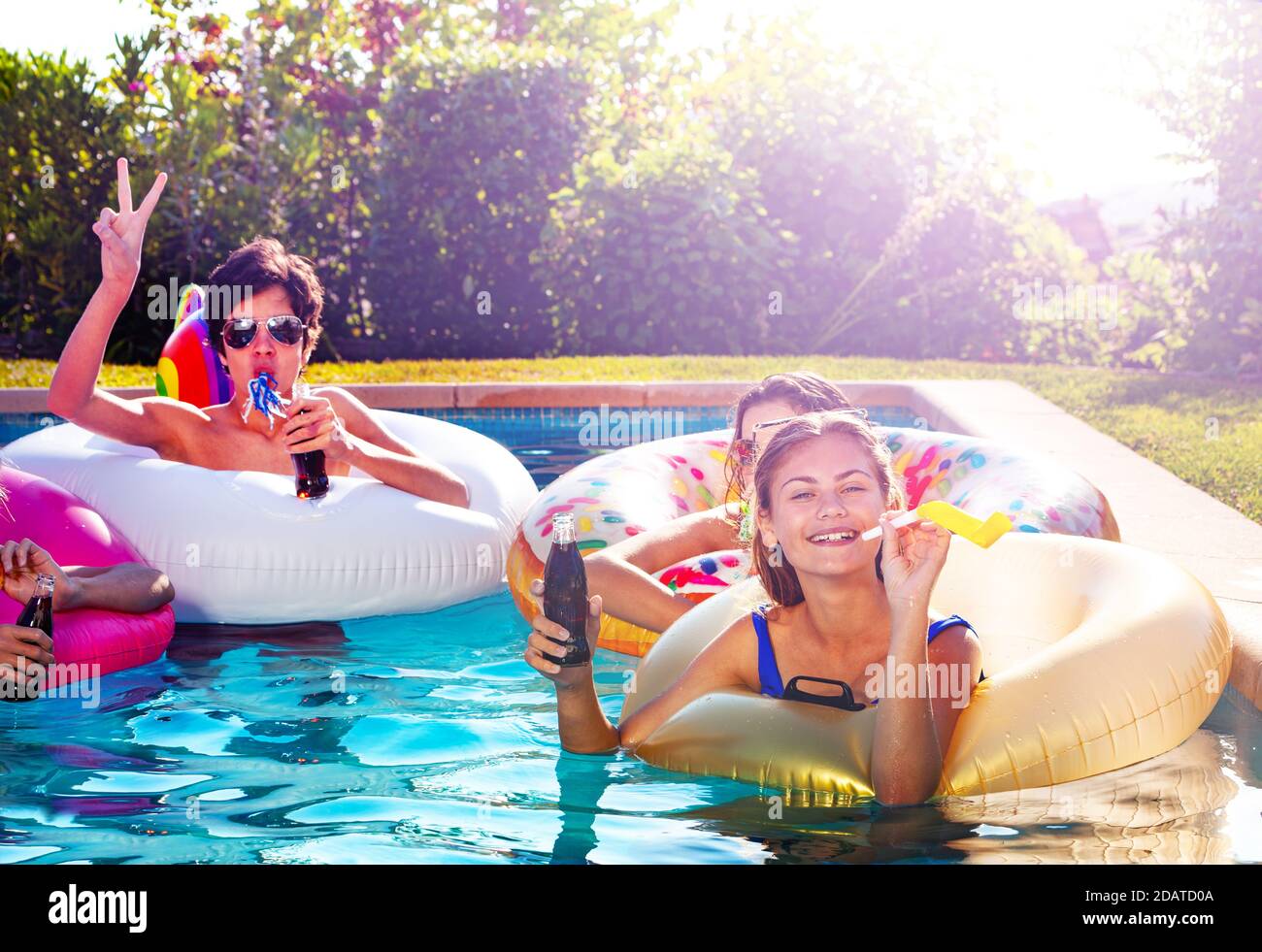 Teen girl hold soda drink and blow noisemaker party with group of