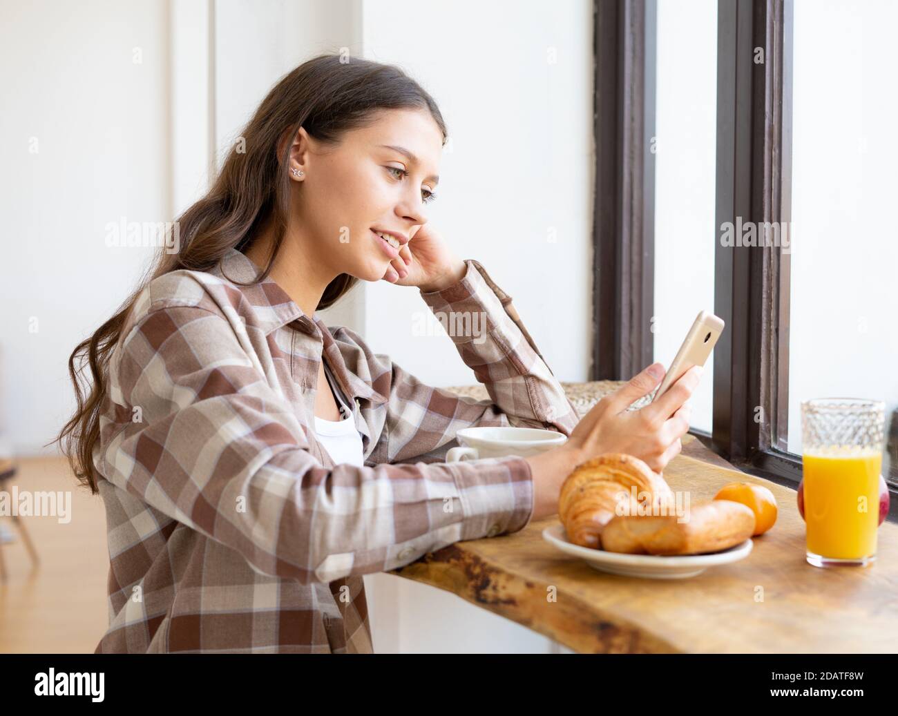 Woman looking for information on Internet, smiling and using mobile, Stock Photo