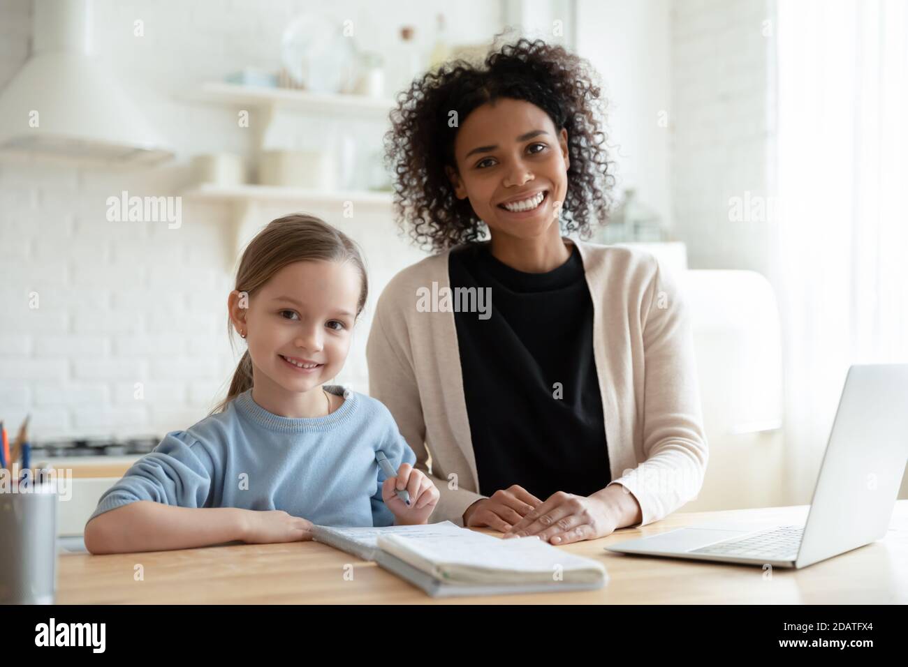 Head shot portrait smiling African American mother with daughter studying Stock Photo