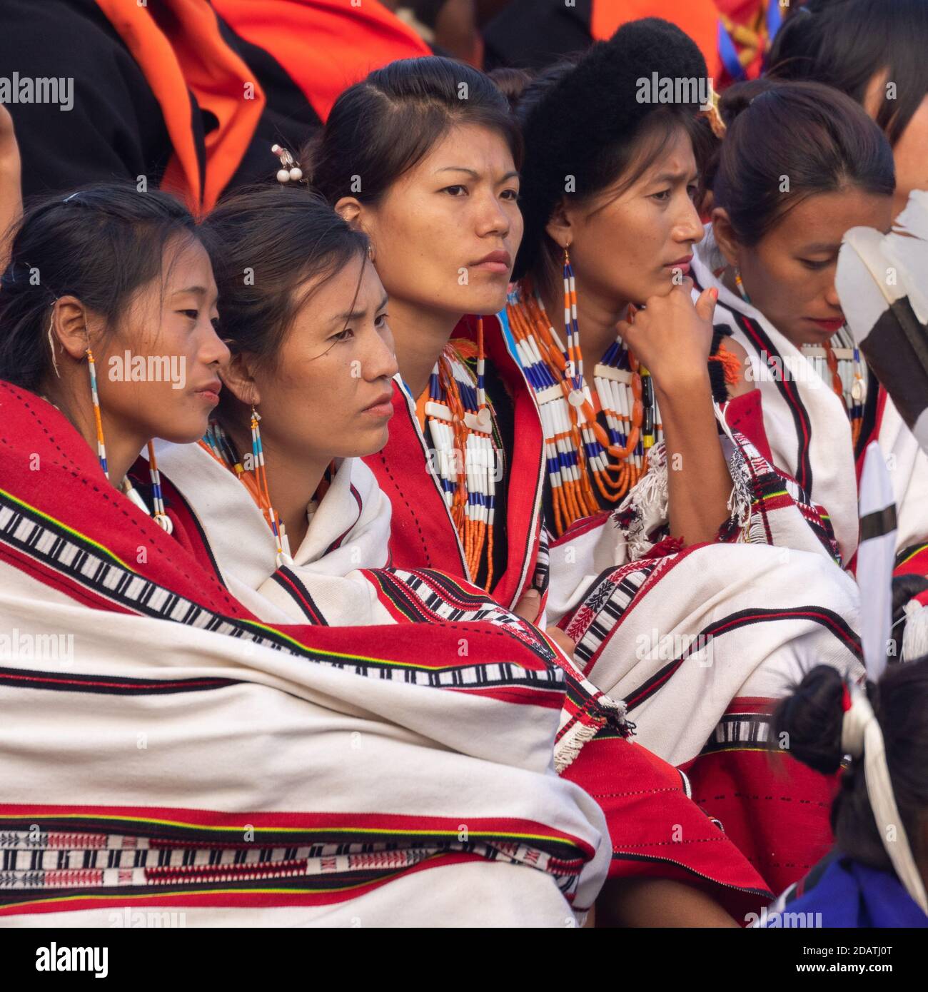 Young Naga tribeswomen siting together wearing colorful attire and shawls in Kisama Heritage village in Nagaland India on 3 December 2016 Stock Photo