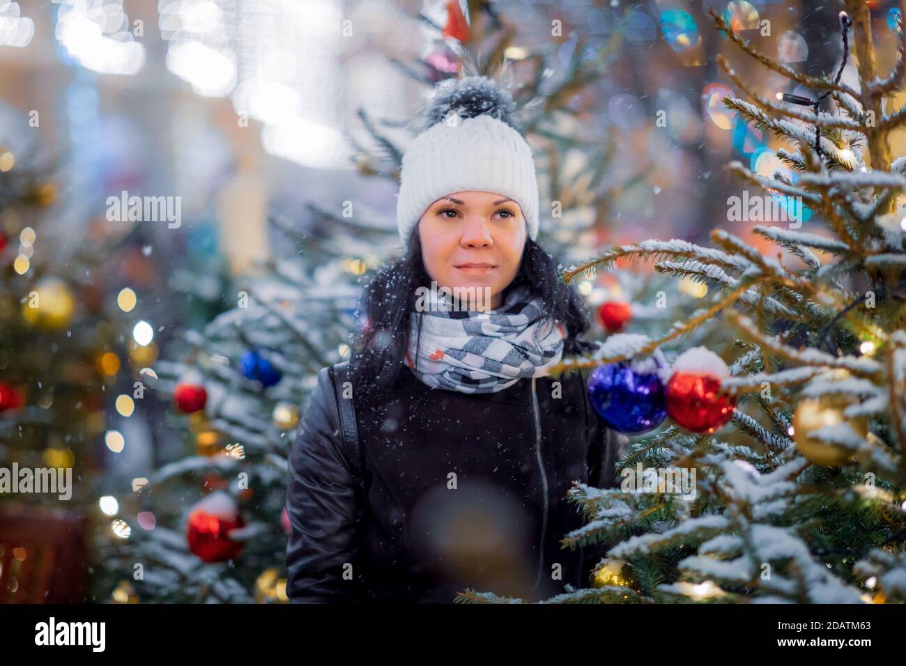 Woman on the street walks on Christmas day next to Christmas trees Stock Photo