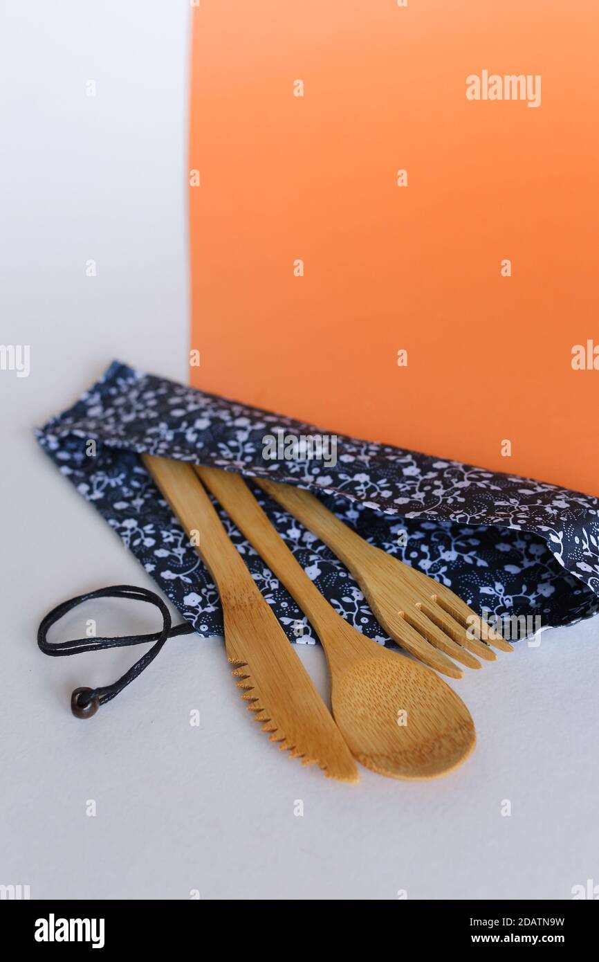 Wooden spoon, fork and knife in tissue pouch in white orange