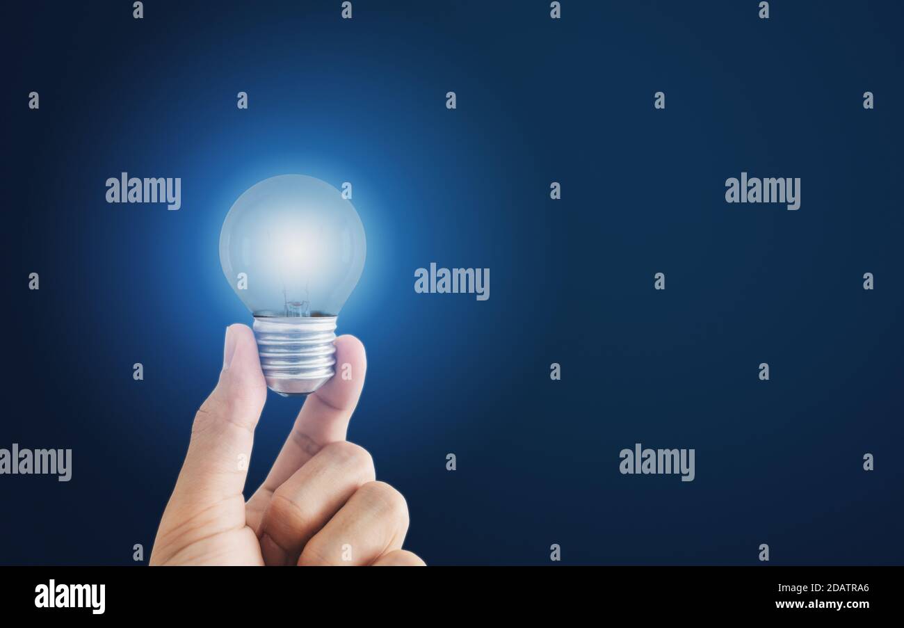 Hand holding glowing light bulb, on blue background Stock Photo