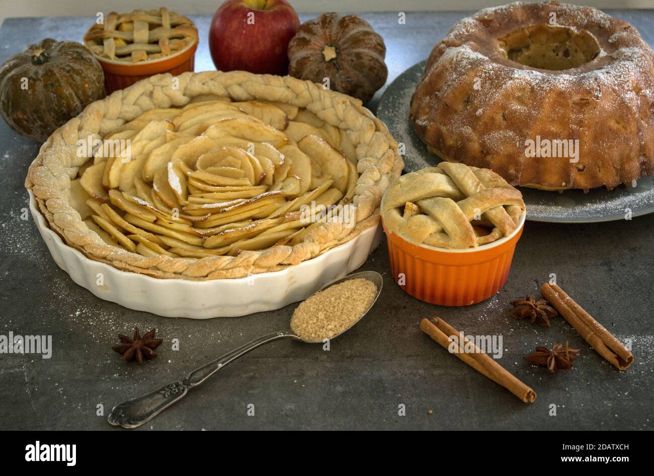 Apple pies of different types on a table with fresh fruits, cinnamon sticks and pumpkins. Autumn  menu ideas. Homemade dessert close up photo. Stock Photo