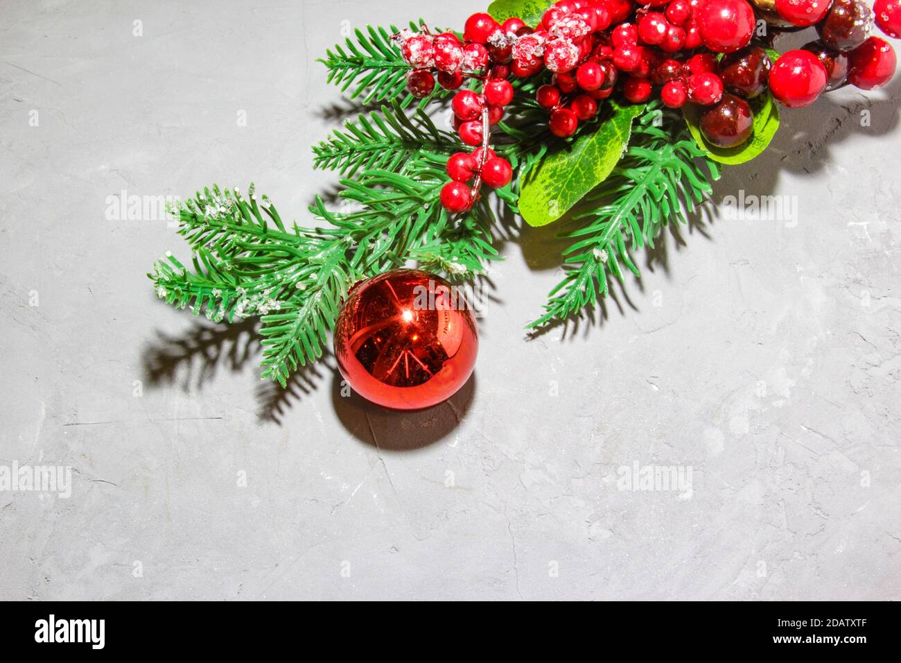 Christmas fir tree branches with red ball, red rowan berries on grey ...