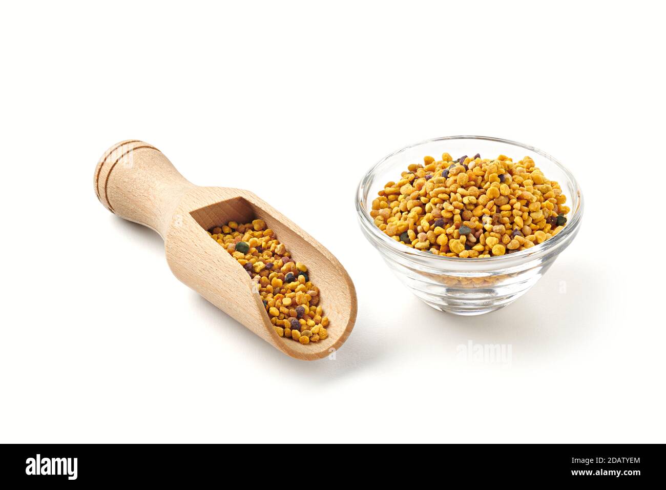 Bee pollen in glass bowl and wooden spoon, over white background, with shadows. Stock Photo