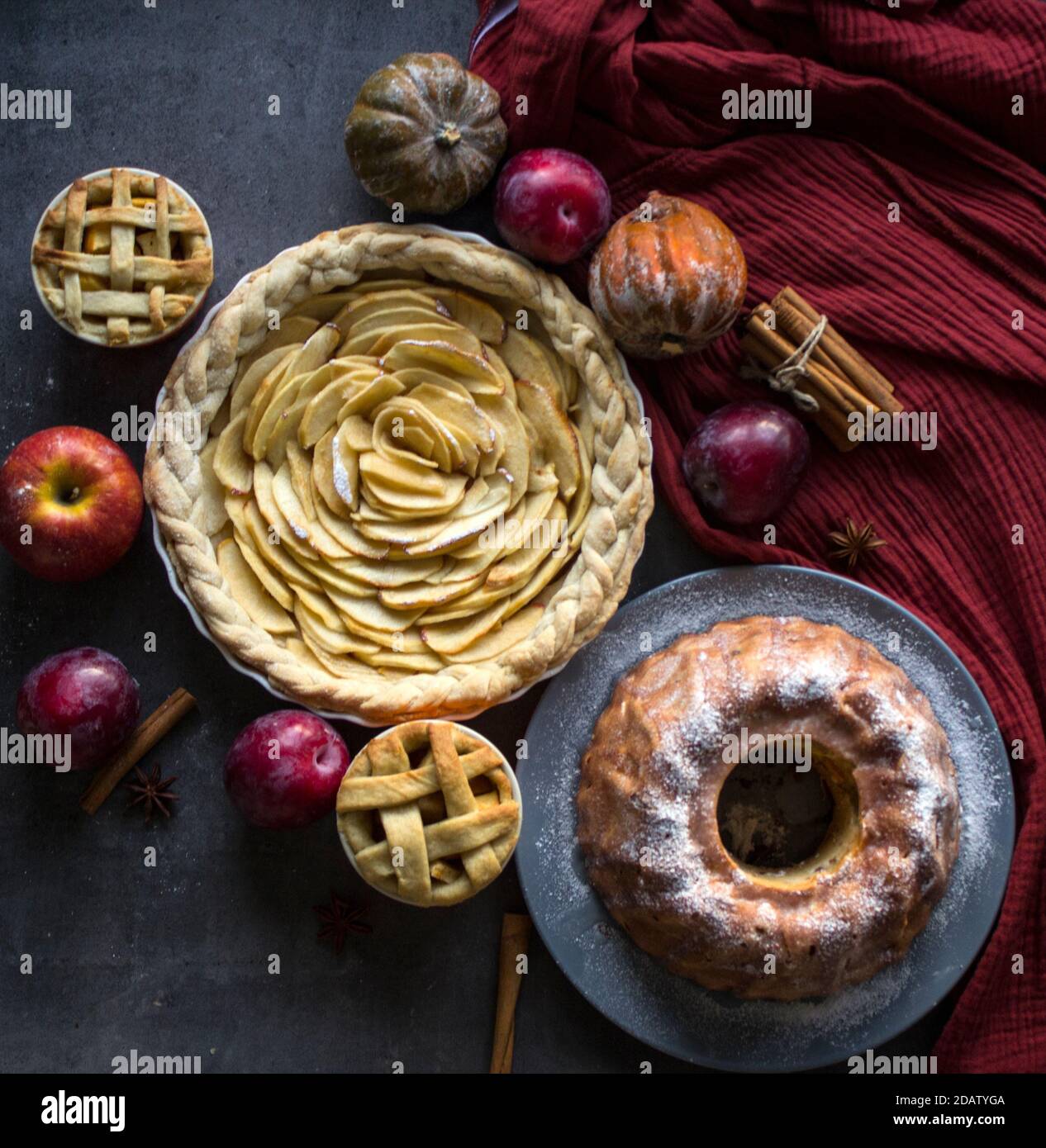 Apple pies of different types on a table with fresh fruits, cinnamon