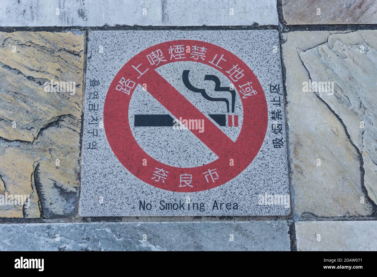 A sign indicating a no smoking area on a pavement on Sanjo Street in Nara, Japan Stock Photo
