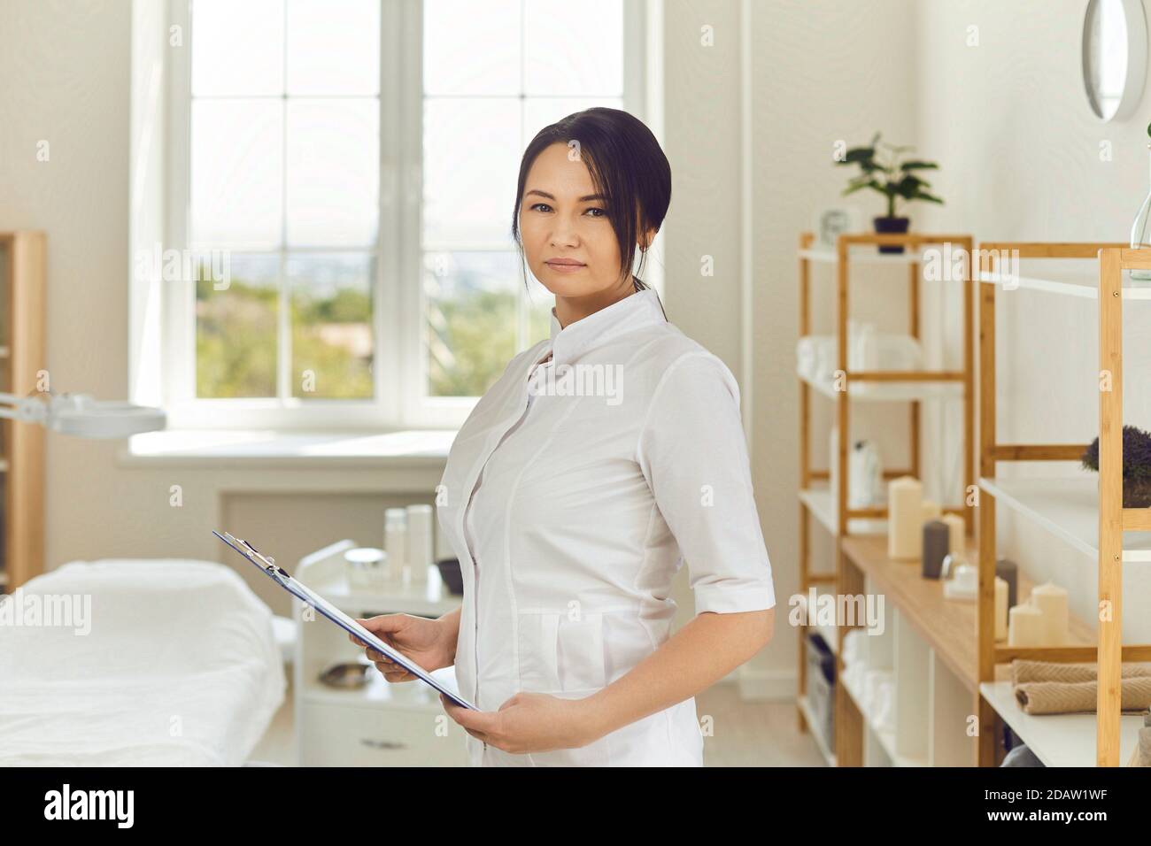 Serious professional beautician standing in her beauty salon and looking at camera Stock Photo