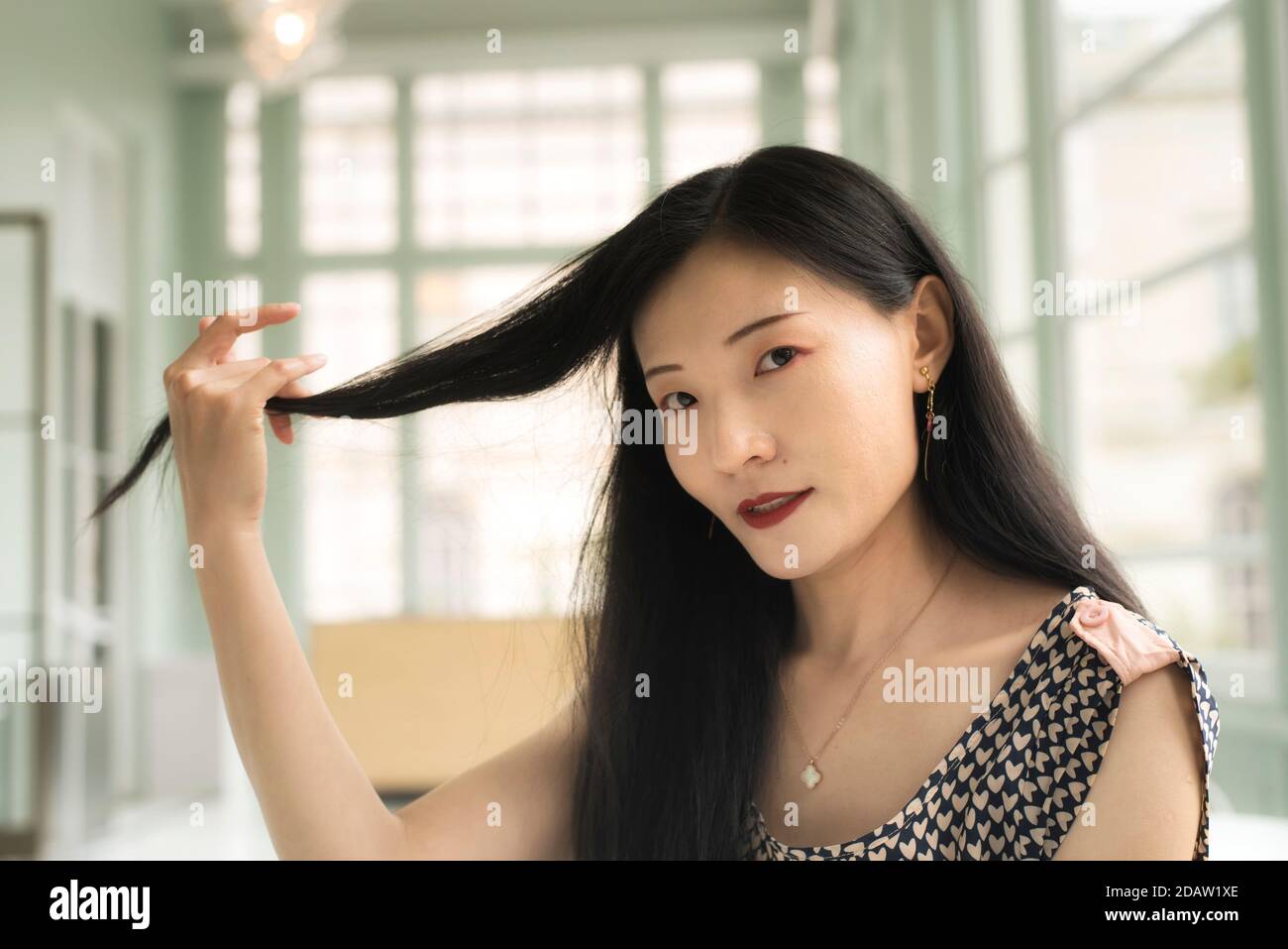 A chinese woman holding her hair inside a sitting room within the walters art museum in baltimore maryland. Stock Photo