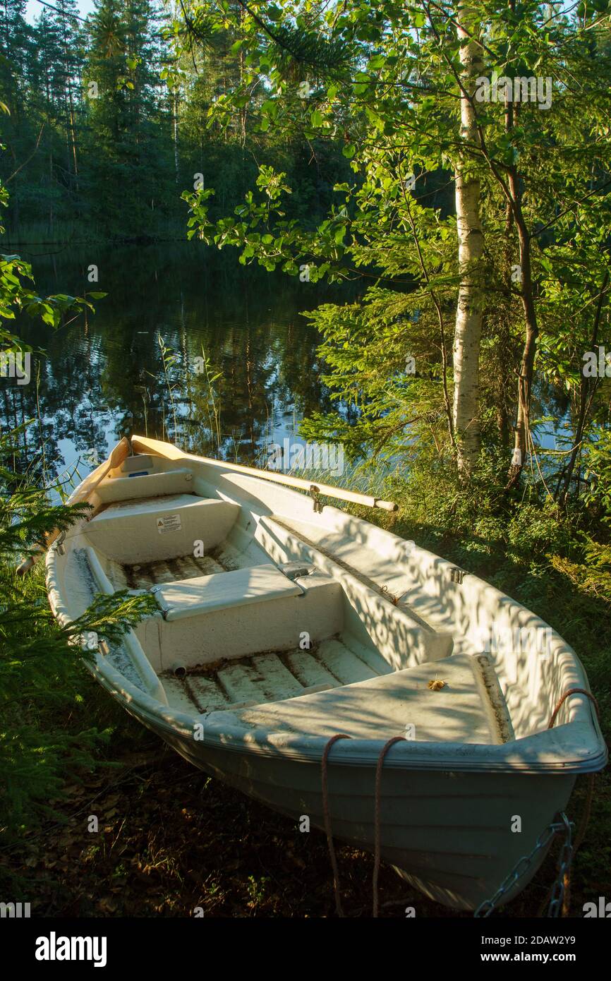 View of a beached small rowboat / skiff by a forest lake at Summer , Finland Stock Photo