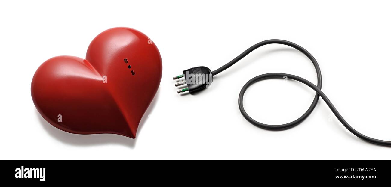 A red heart with an electrical socket and an electrical plug next to it, on a white background. Stock Photo