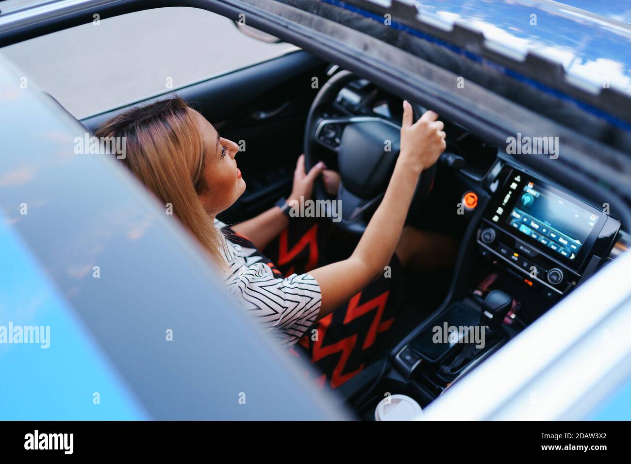 Young woman driving with sunroof open Stock Photo Alamy