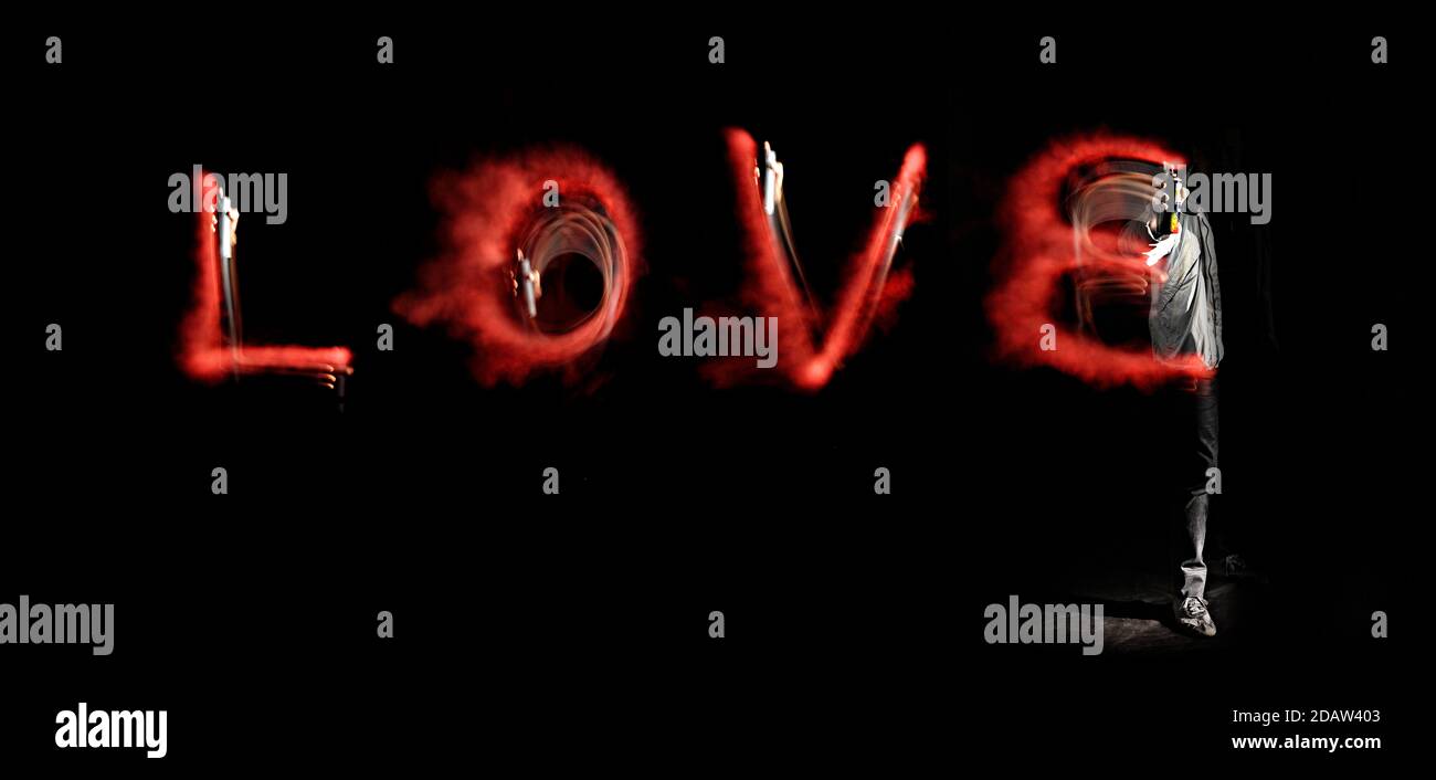 The word Love written with a spray can in the air, on a black background. Stock Photo