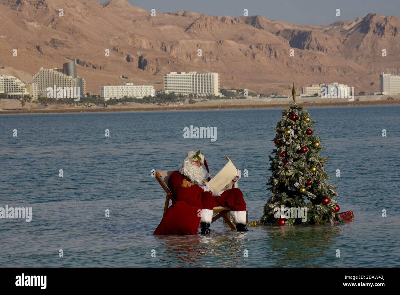 Ein Bokek, Israel. 15th Nov, 2020. Jerusalem Santa Issa Kassissieh reads a scroll on a salt formation in the Dead Sea, the lowest place earth, in Ein Bokek, Israel on Sunday, November 15, 2020. The photo event was organized by the Israel Ministry of Tourism to encourage tourism to the Dead Sea ahead of the Christmas holiday. Incoming tourism to Israel has received a severe blow due to the global coronavirus pandemic and the closure to incoming tourists since March. Photo by Debbie Hill/UPI Credit: UPI/Alamy Live News Stock Photo