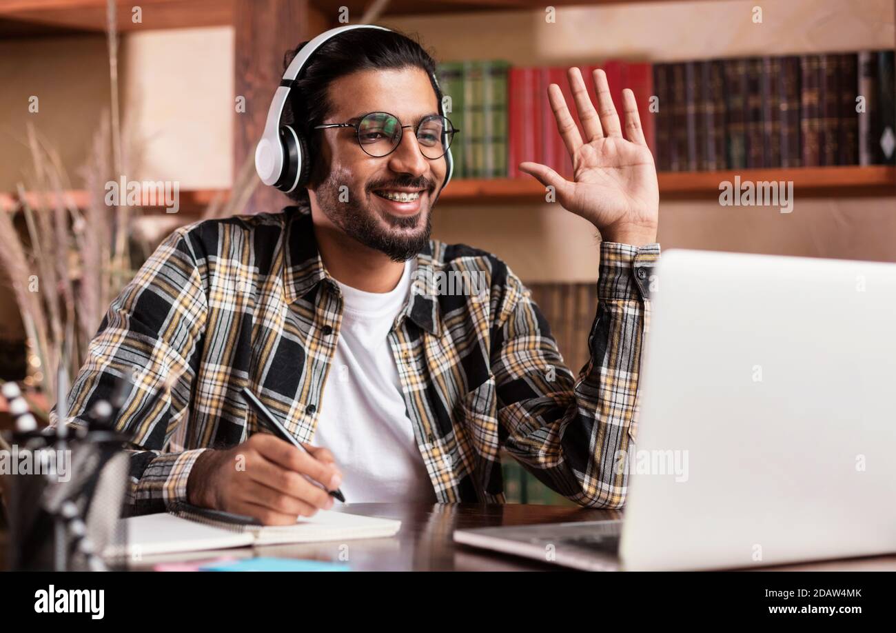 Arab Student Guy At Laptop Waving Hello Learning At Home Stock Photo