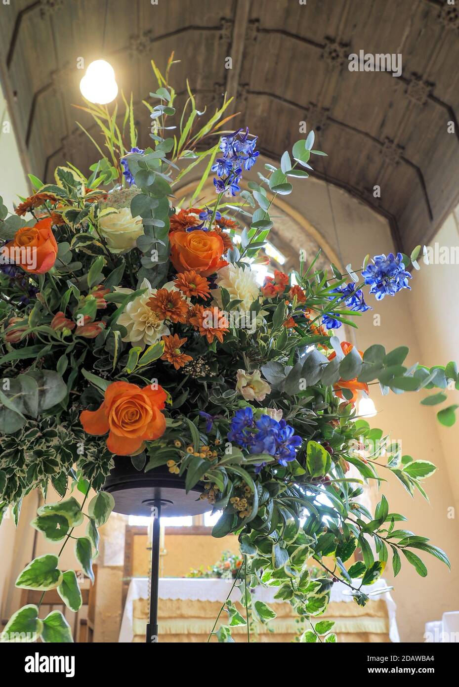a splayed flora arrangement from below in christian church under a timber roof backlit with background altar Stock Photo