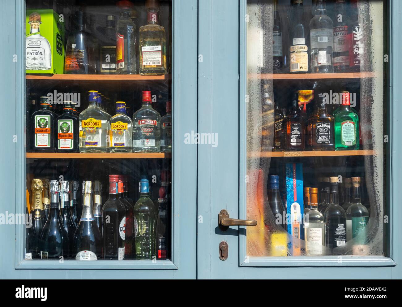 Athens, Greece. November 10, 2020. Alcohol spirits bottles display, Store shelves behind a blue glass door, city center downtown Stock Photo