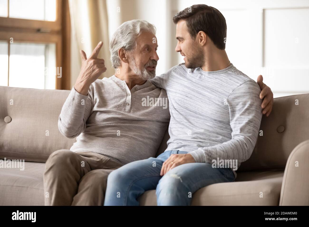 Happy older father and son having pleasant conversation at home Stock