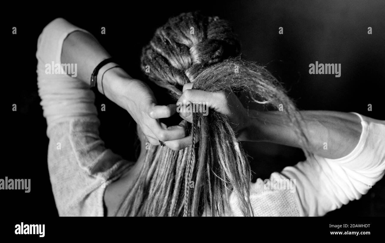 The woman is braiding her braid. Dreadlocks on the head, hairstyle. Stock Photo