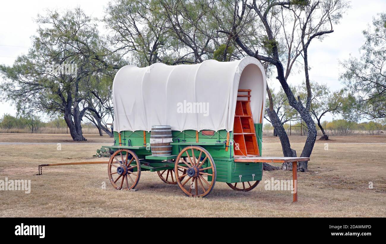 Old wild west covered wagen in Texas with mesquite trees in background. Stock Photo