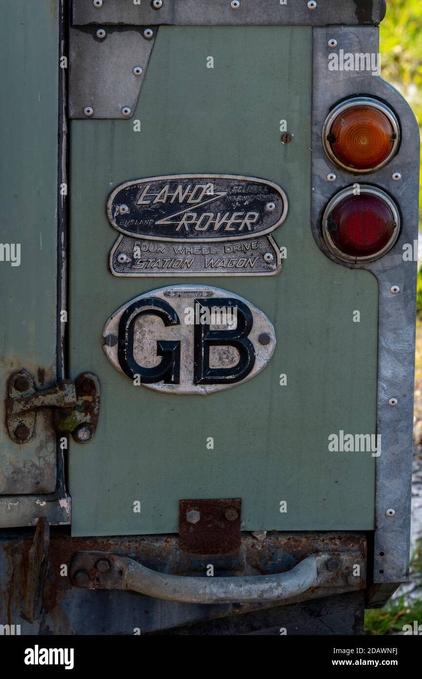 The rear of an old series Land Rover with gb sticker and old fashioned Land Rover badge next to spare wheel carrier Stock Photo
