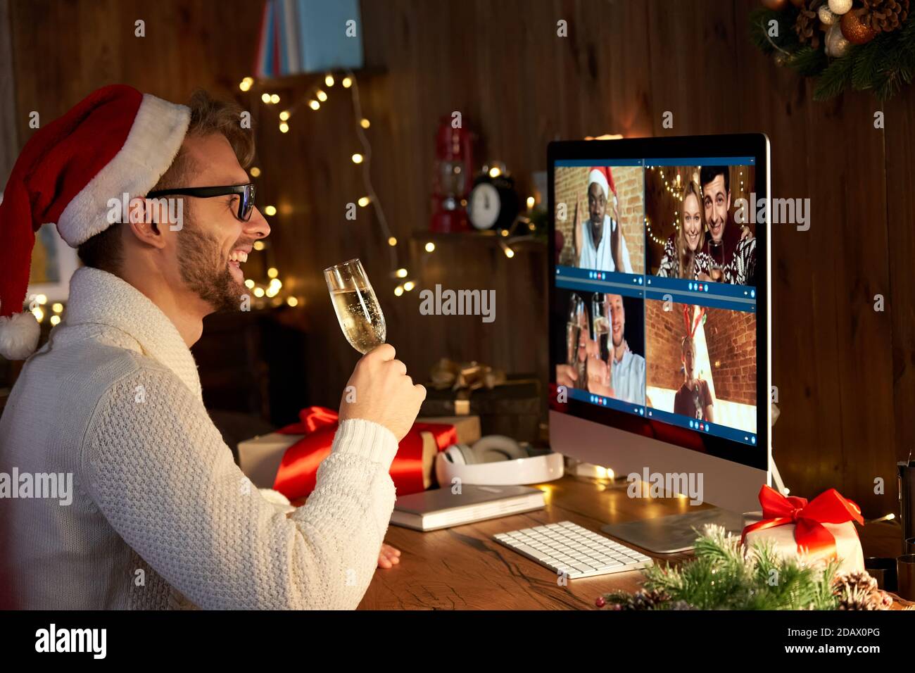 Happy man wears santa hat celebrating New Year party with friends on video call. Stock Photo