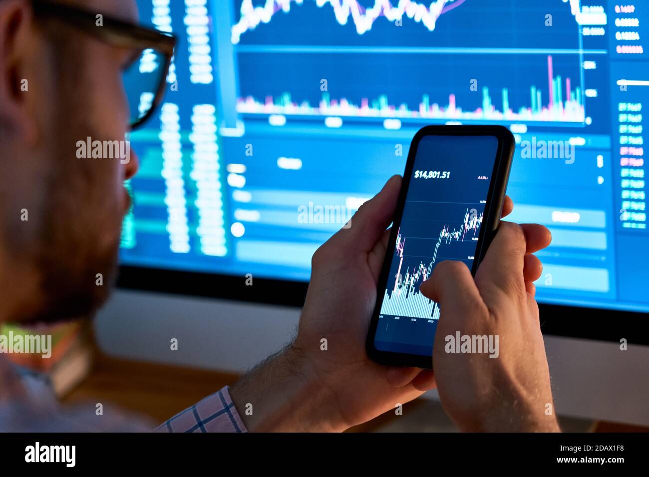 Trader using mobile phone app analytics for stock trading graph data analysis. Stock Photo