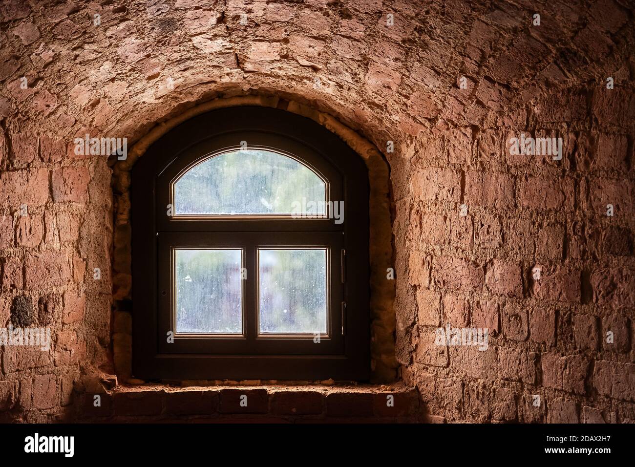 Brown window with an arch in a recess in the wall made of old red brick. From the window of the world series. Stock Photo