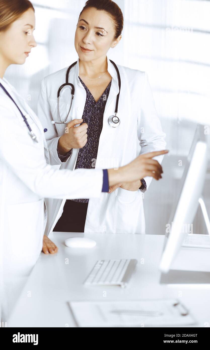 Two Physicians Two female physicians are discussing medical therapy, while standing at ...