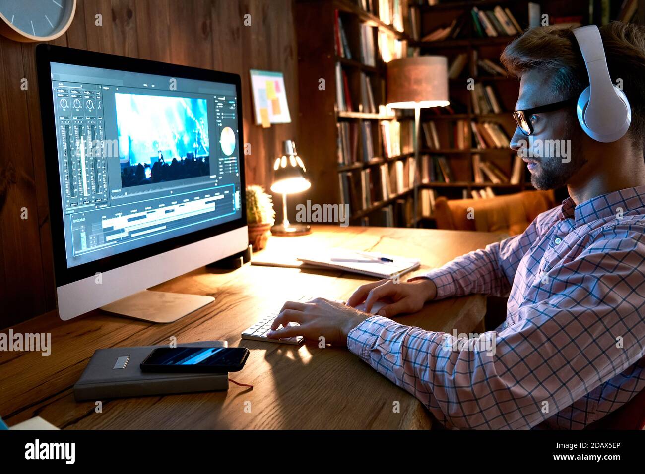 Male videographer editor using pc computer editing footage at home office. Stock Photo