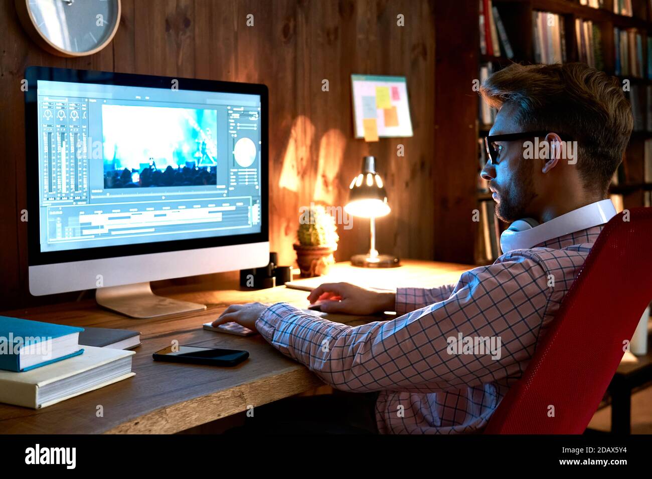 Male videographer using computer editing video footage visual content. Stock Photo